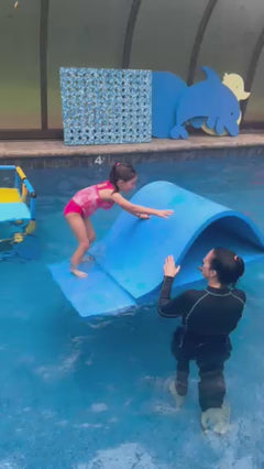 Child sliding down the foam pool waterslide to an instructor